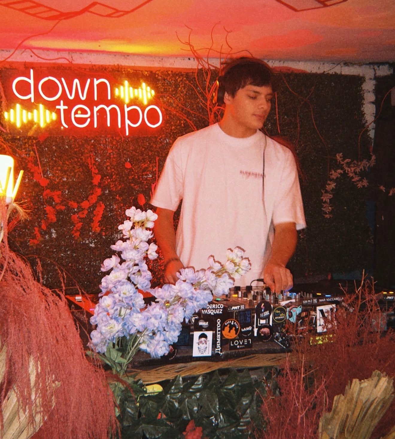 Ale Szpin ajustando la consola entre flores y luces rojas
