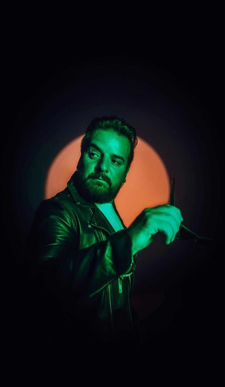 Retrato de Esteban Toledo bajo luces verdes con anteojos en la mano
