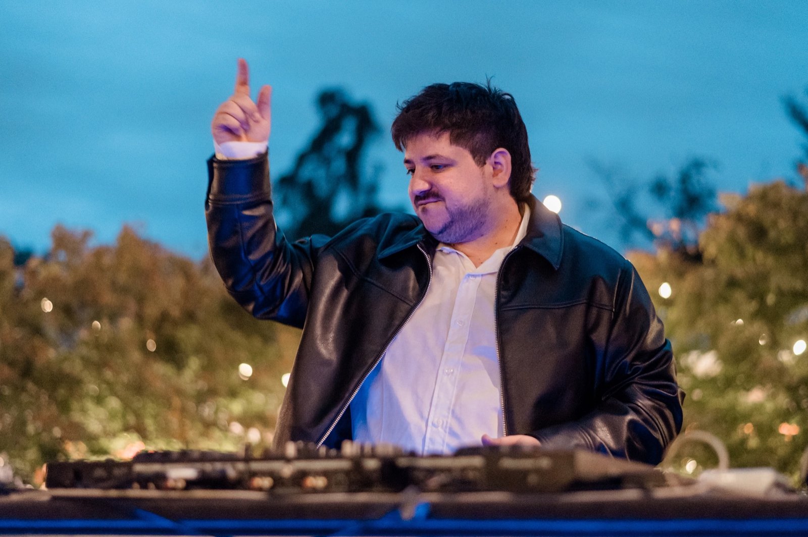 Fede Ibarra levantando una mano detrás de la consola al aire libre