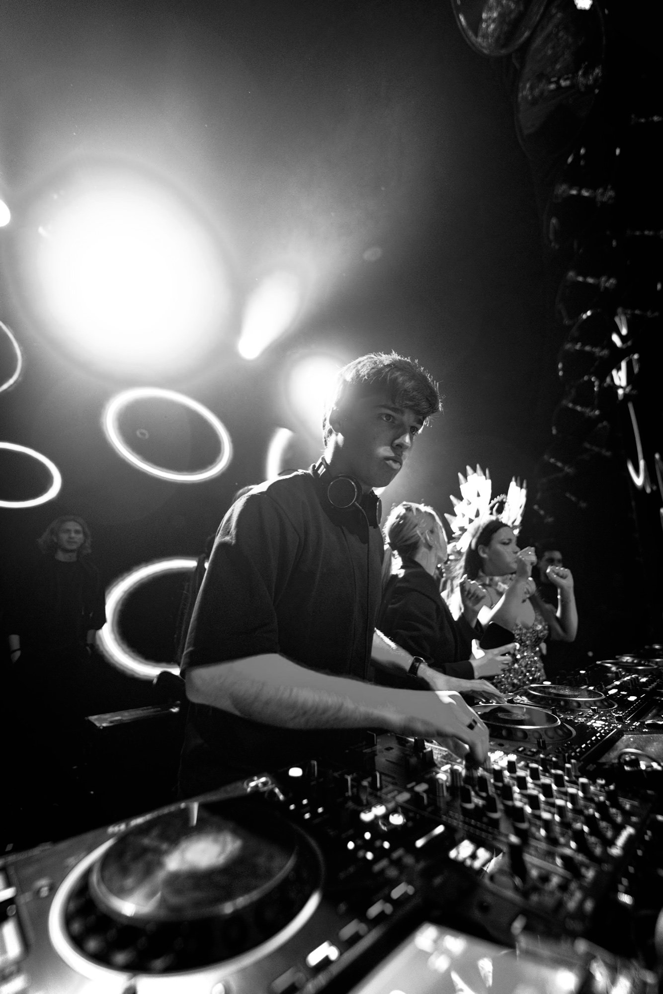 Fran Larrea mezclando con auriculares al cuello entre luces circulares en blanco y negro